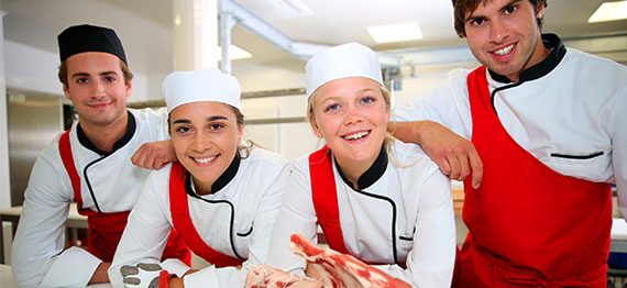 Happy team of young butchers in school kitchen