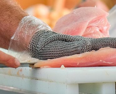 BEER-SHEVA ISRAEL - JUNE 28 2016: The hands of a butcher cutting slices of raw chicken breast