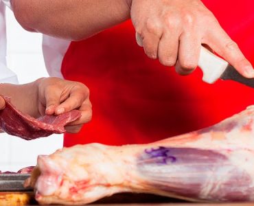 Mature butchers working together at counter in butchery